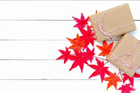 Christmas gift boxes and red maple on white wooden background. Top view with copy spaceの写真素材