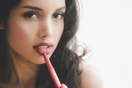 Beautiful luxury young woman applying lip liner to nude red lips. Close up shot and make up cosmetic of woman putting lipstick on her lipの写真素材