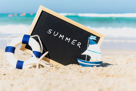 Closeup of a chalkboard with the text summer written on the sand of a beach. Summer Conceptの写真素材