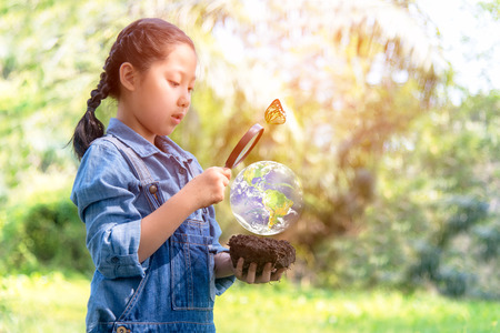 Asian girl holding magnifying glass finding Growth plants in the Green world, plants nurture environmental reduce global warming earth, Ecology and Saving World.の写真素材