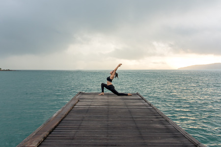 Healthy woman lifestyle balanced yoga practicing meditate and energy on the bridge in morning the seashore. Healthy Concept.の写真素材