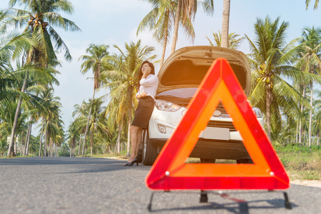 Business woman with a broken car calling for assistance.