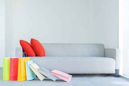 Shopping online. Colorful shopping bags with red pillow on sofa in the living room.の写真素材