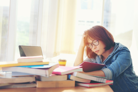 Asian asian women reading something in a book and taking notes at college library.  Education ...