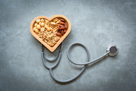 Healthy Foods. Mixed nuts in heart shape and stethoscope with nuts for diet on a concrete background. Different kinds of tasty and healthy nuts. Top view and copy space.  Healthy Conceptの写真素材