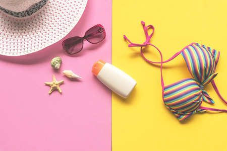 Summer Fashion woman swimsuit Bikini, camera, starfish, sunblock, sun glasses, hat. Travel in the holiday pastel background.  Summer Concept.の写真素材