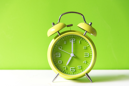 Alarm green  vintage alarm clock falling on the floor with color background.  Morning and Start up...