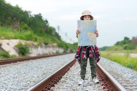 Student asian girl and traveler with backpack adventure holding map to find directions near train station outdoor for study and education nature. Travel and Lifestyle Conceptの写真素材