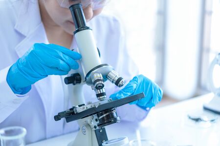 Scientists analyzing study data and evaluating microscope. Health care researchers doing some research with dropper chemical testing and working in life science laboratoryの写真素材