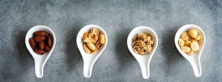 Healthy Foods. Mixed nuts in white bowls with nuts for diet on a concrete table. Different kinds of tasty and healthy nuts for text banner. Top view and copy space. Healthy Conceptの写真素材