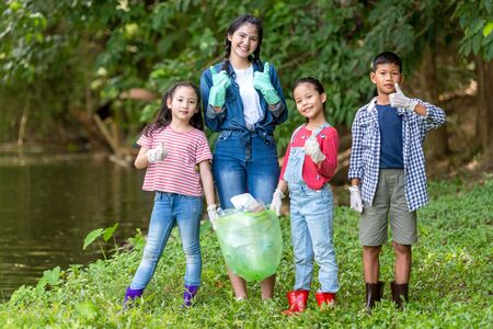 Group family asian children collecting garbage and plastic on the river to dumped into the trash for...