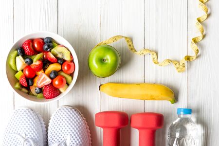 Healthy lifestyle for women diet with dumbbells sport equipment, sneakers, measuring tape, fruit...
