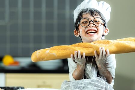 Lifestyle Family. Smiling chef asian kid boy cooking toast and make  bread for dinner.  People children making and leaning sweet food, so happy and enjoy.  Family Concept.の写真素材