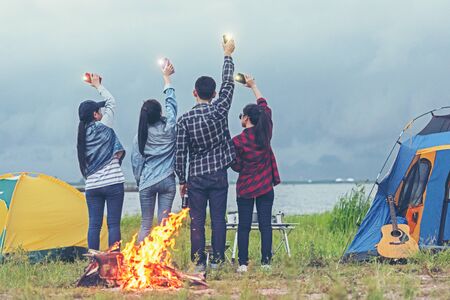 Party Camping.  Group asian family and friends travel enjoy party and roasted sausages relax in...