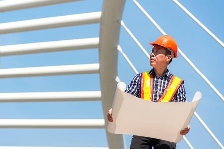 Architect engineer planning blueprint in construction city site. Workers security control. City...