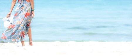 Summer Holiday. Lifestyle woman chill holding big white hat and wearing dress fashion summer trips standing chill on the sandy ocean beach. Happy people enjoy and relax vacation. Lifestyle and Travel Concept.  copy space and banner for textの写真素材