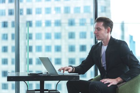 Businessman using tablet computer to work with financial data in the modern office, relax and rest time after work.  City background. Business Concept.の写真素材
