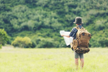 Asian boy backpack checking map in jungle forest, trips adventure and tourism for destination and leisure for education and relax in nature park .  Travel vacations Conceptの写真素材