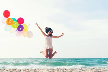 Asian young woman happy  jumping with balloon congratulation and celebrate in Happy New year 2020 for change new life future concept. Freedom lifestyle jump as part of Number 2020 success on the sand beach outdoor.  Vintage Toneの写真素材