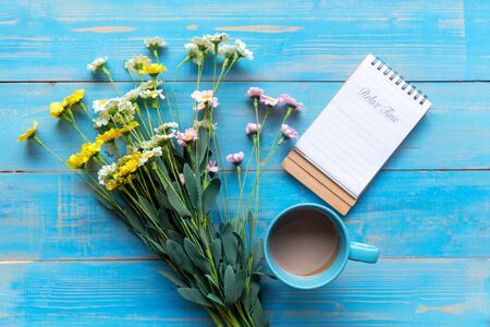 Cozy winter relax time.  Cup of hot coffee with write note on paper and flower on the blue wood background in morning sunny day. Lifestyle conceptの写真素材