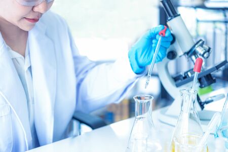 Scientists analyzing study data and evaluating microscope. Health care researchers doing some research with dropper chemical testing and working in life science laboratory.の写真素材
