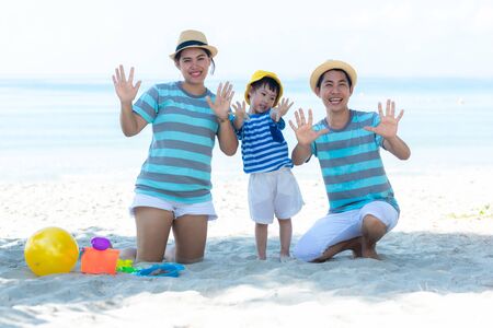 Asian happy family have fun and play yellow ball on the beach.  Family people tourism travel in summer and holiday  for leisure and destination. Travel and Family Conceptの写真素材