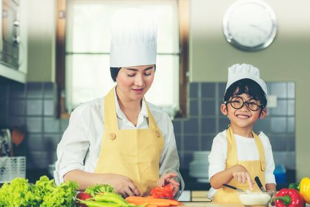 Cooking Family. Chef parent and kid boy make fresh vegetables salad for healthy eat.  Asian son helping make food, so happy and enjoy.  Family Lifestyle Conceptの写真素材