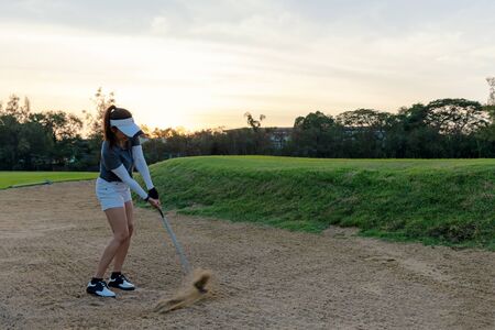 Profession asian Golfer woman hitting out of a sand trap. People with the golf course is on the sand.  Hobby in holiday and vacations on club golf. Lifestyle and Sport Concept
の写真素材