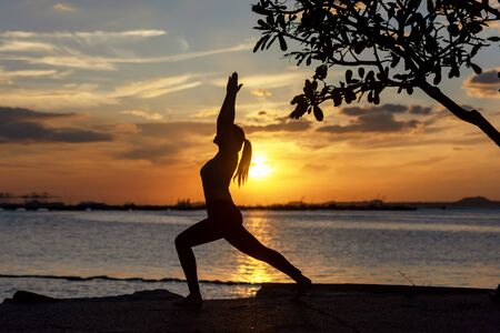 Lifestyle woman yoga exercise and pose for healthy life.Â  Young girl or people pose balance body vitalÂ  zen and meditation for workout silhouette sunset nature background. Healthy Conceptの写真素材