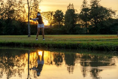Golfer sport course golf ball fairway.Â  People lifestyle woman playing game golf tee of on the green grass sunset background.Â  Asia female player game shot in summer.Â  Healthy and Sport outdoorの写真素材