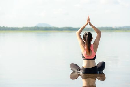 Yoga woman sitting zen and meditation for workout healthy life in sunrise morning. Young girl or people pose balance body vital  and exercise in nature background. Health care and Lifestyle Conceptの写真素材