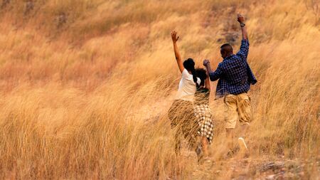 Happy family running and relax on nature field meadow at sunset.  People African luggage and enjoy fun and relax leisure destination in holiday. Travel and Family Conceptの写真素材