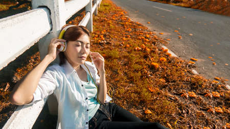 Lifestyle people girl relax and listening music and work from home on the grass in nature park outdoors. Young Woman stay home and resting in summer vacations.の写真素材