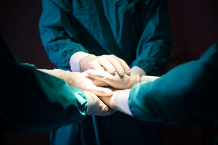 Group Surgeon doctor joining hands before Patient surgery in hospital operating theater .   Teamwork medical doctor working  performing surgeryの写真素材