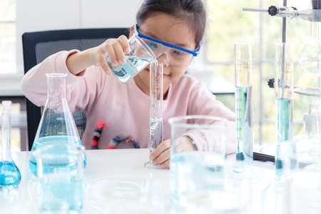 select focus. Asian children analyzing study evaluating microscope with scientist. Health care researchers doing some research with dropper chemical testing and working in life science laboratoryの写真素材