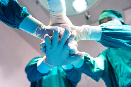 Group Surgeon doctor joining hands before Patient surgery in hospital operating theater .   Teamwork medical doctor working  performing surgeryの写真素材