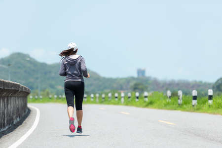 Asia lifestyle woman runner running through the road.  People sport outdoor workout and exercise jogging in a road dam. Weight Loss and Healthy Conceptの写真素材
