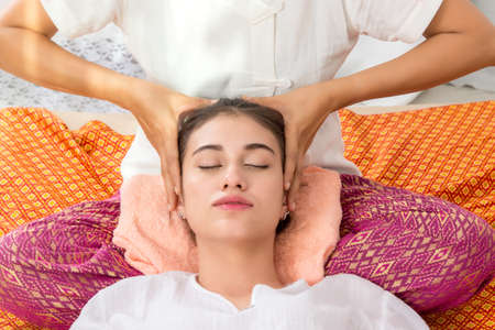 Thai Masseuse doing massage for woman in spa salon. Asian beautiful woman getting thai herbal...