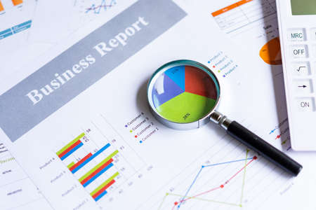 Magnifying glass on pie chart with statistics accounting info which including of many economic statistics business.  Business Conceptの写真素材