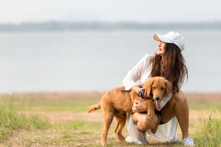 Asian lifestyle woman playing with dog golden retriever friendship so happy and relax outdoor the summer field meadow park.の写真素材