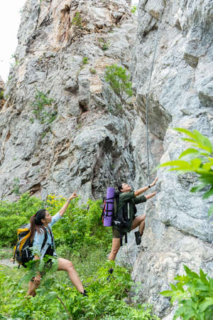 Group Hiker woman helping her friend climb up the last section of sunset in mountains. Traveler teamwork walking in outdoor lifestyle adventure and camping. Travel Concept.の写真素材