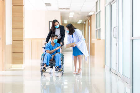 Group of medical staff discussing and report in hallway hospital.  Healthcare professional taking and consoling with patient in wheelchair.の写真素材