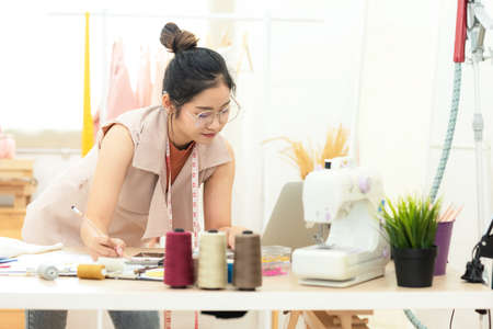 Owner business asian young women fashion designer working on her designer in the showroom,  Lifestyle Stylish tailor press clothes in studio.  Business and Industry small Conceptの写真素材