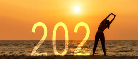 Happy New Year Card 2021. Silhouette lifestyle woman relax and freedom on sea beach in the sunset as Start up success 2021.  Holiday Conceptの写真素材