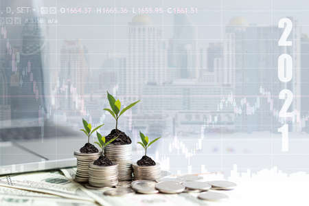 2021 New year on growing up money coin stack for investment.  Economic and business growth in 2021, planning financial report for investor real estate business, city background.の写真素材