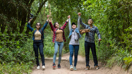 Group asian friends traveler with backpack adventure raise arm and walking relax in the jungle...