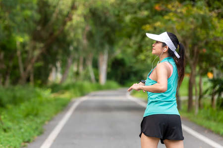 Healthy woman warming up in the road outdoor. Asian runner woman workout before fitness and jogging session at the park. Healthy and Lifestyle Concept.の写真素材