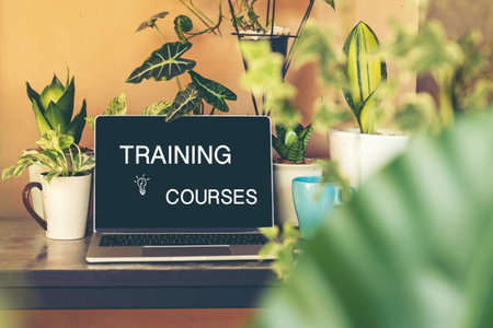 Training courses Online text on laptop screen on table with plant and coffee cup in the nature garden at home. Technology and Education Conceptの写真素材