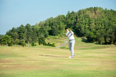 Golfer asian man use iron swing and hitting golf ball practice at golf driving range and fairway in sunny morning day on club golf. Lifestyle and Sport Conceptの写真素材
