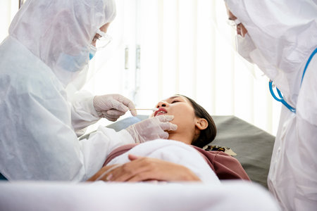 Medical  taking test swab for   virus sample from potentially infected patient women.  Doctor suits and surgical face mask for protectの写真素材